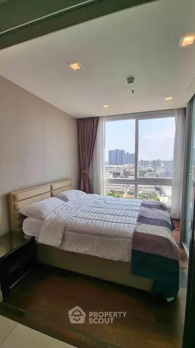 Modern bedroom with large window offering stunning city view in high-rise apartment.