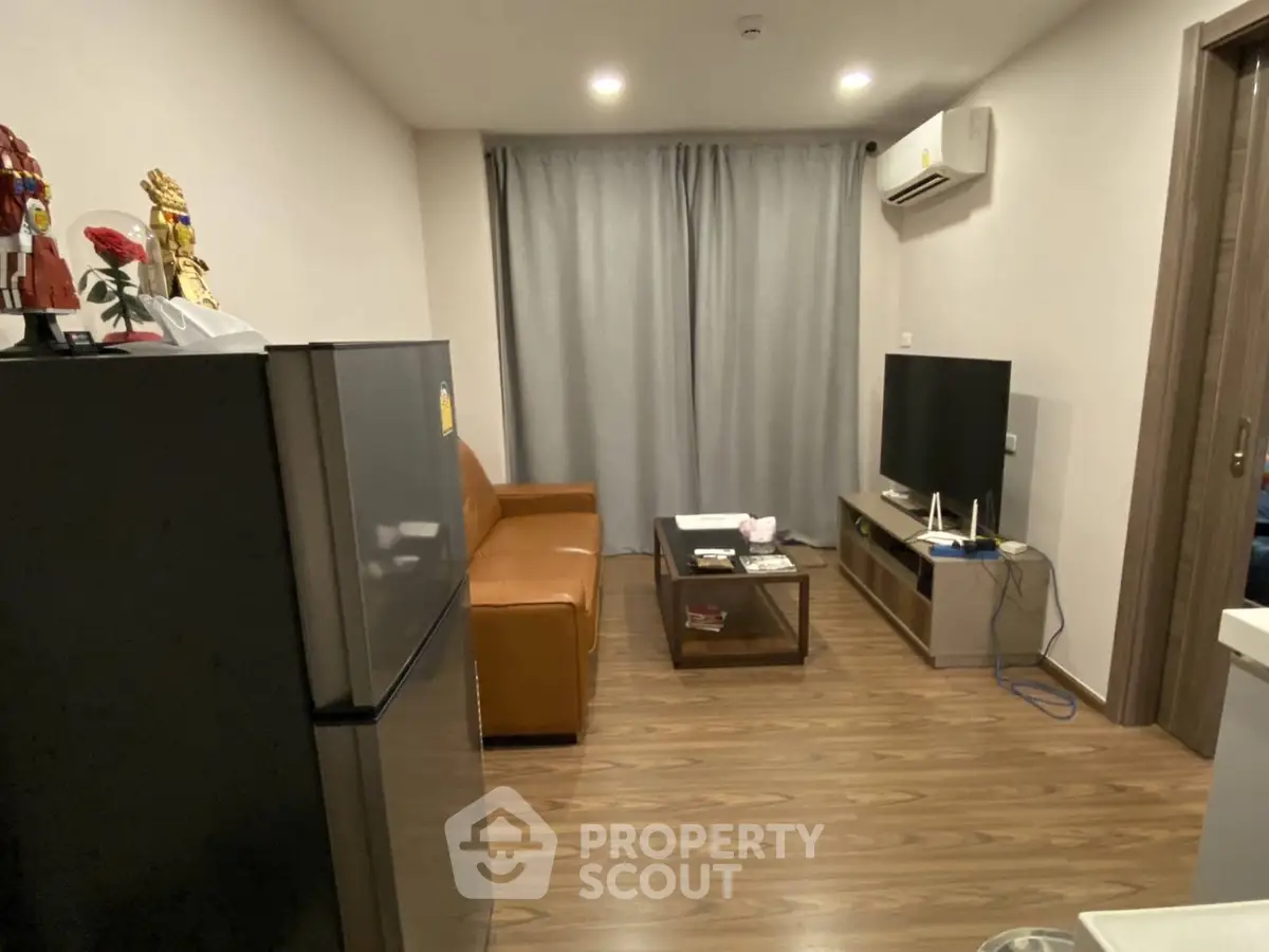 Cozy living room with modern decor, featuring a comfortable sofa, flat-screen TV, and sleek wooden flooring.