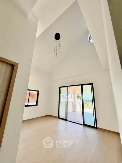 Spacious modern room with high ceiling and large sliding doors to balcony