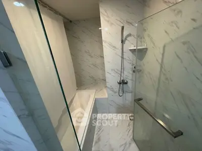 Modern bathroom with marble tiles and glass shower enclosure