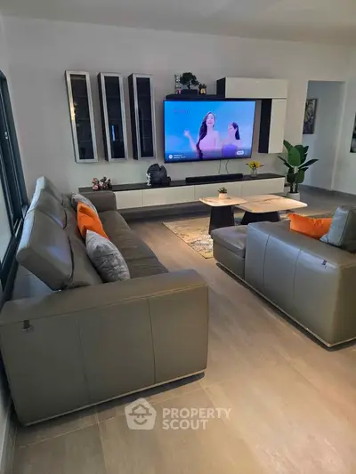Modern living room with sleek furniture and wall-mounted TV, perfect for relaxation and entertainment.