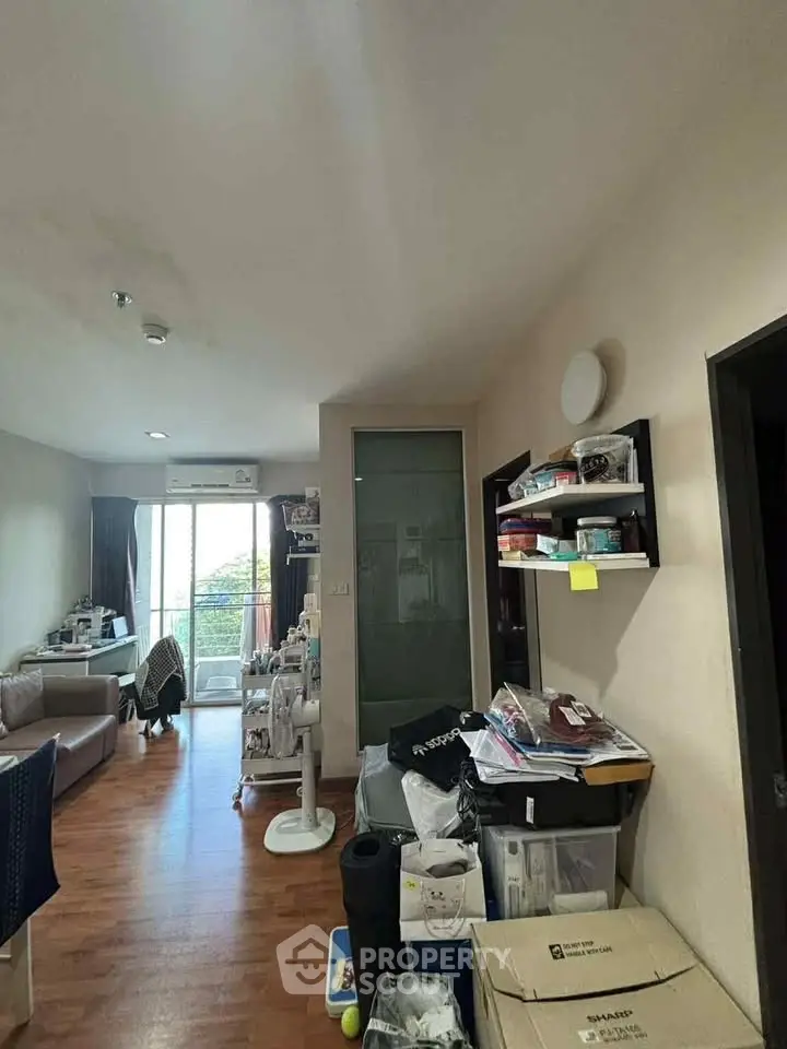 Cozy living room with wooden flooring and balcony access, perfect for urban living.