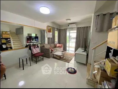 Spacious living room with modern decor and natural light, featuring a cozy seating area and staircase.