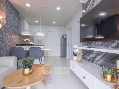 Modern living room with stylish decor and open kitchen layout, featuring elegant furniture and a sleek TV setup.