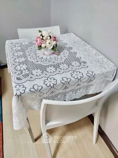 Charming dining nook with elegant lace tablecloth and floral centerpiece, perfect for cozy meals.