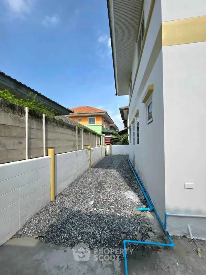 Side view of a modern house with gravel pathway and blue sky