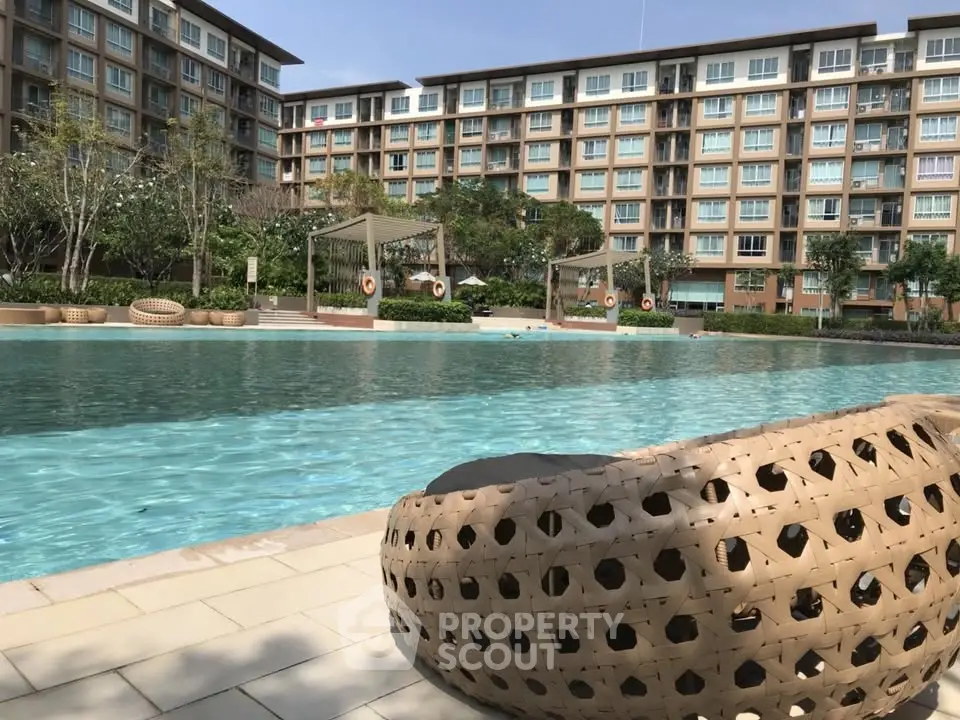 Luxurious apartment complex with stunning pool and modern outdoor seating.