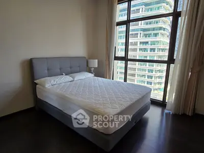 Spacious bedroom with large windows and modern bed in high-rise apartment
