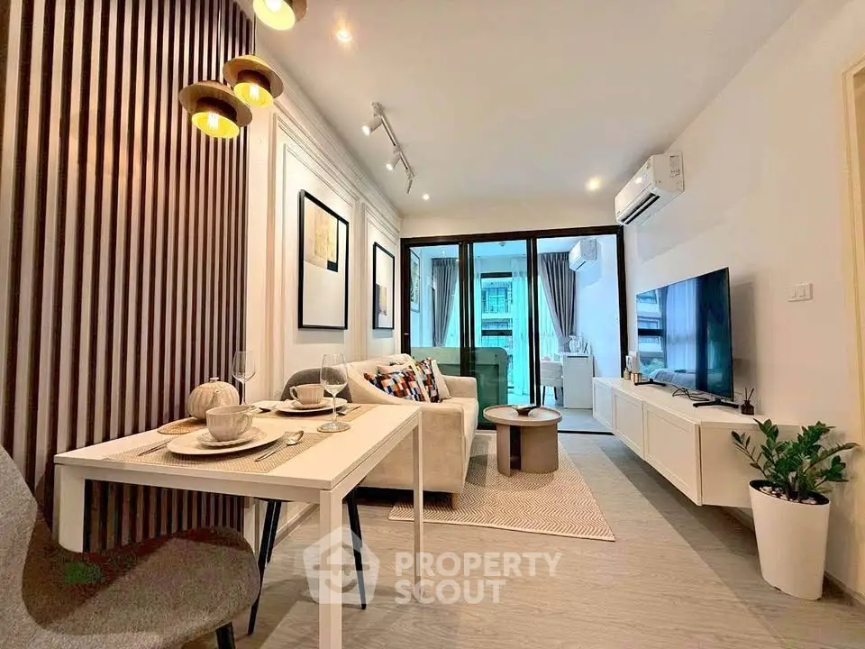 Modern living room with stylish decor and open layout leading to a balcony, featuring elegant lighting and contemporary furniture.
