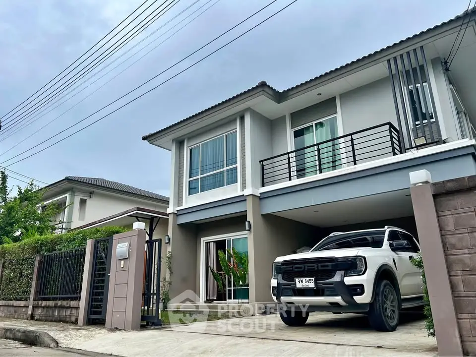 Modern two-story house with balcony and driveway in a suburban neighborhood.