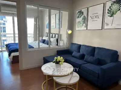 Modern living room with blue sofa and stylish decor adjacent to a cozy bedroom with balcony view.