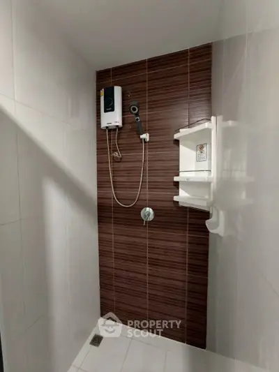 Modern bathroom shower area with sleek brown tiles and water heater.