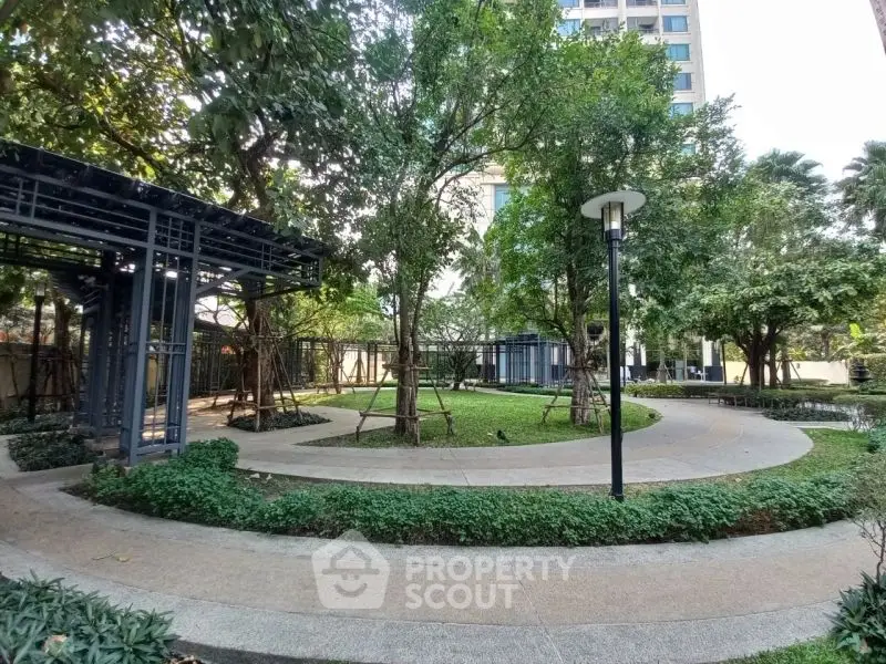 Serene garden area with lush greenery and modern architecture in a residential complex.