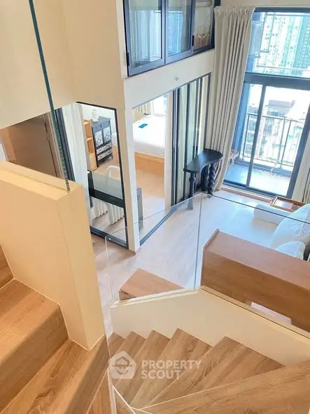 Modern duplex apartment with wooden staircase and large windows offering city views.