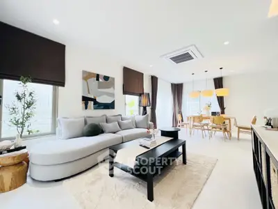 Elegant modern living room with stylish decor and open dining area, featuring natural light and contemporary furniture.