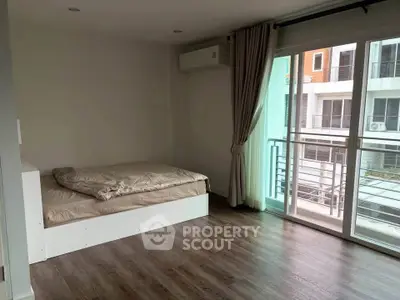 Spacious bedroom with large window and balcony access in modern apartment.