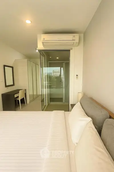 Modern bedroom with air conditioning and sliding glass doors to balcony.