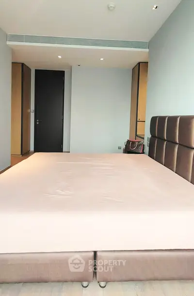 Spacious bedroom with modern design and ample natural light, featuring a large bed and sleek furnishings.