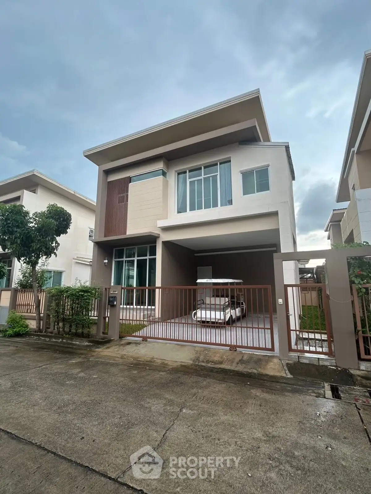 Modern two-story house with a sleek design and spacious driveway in a serene neighborhood.