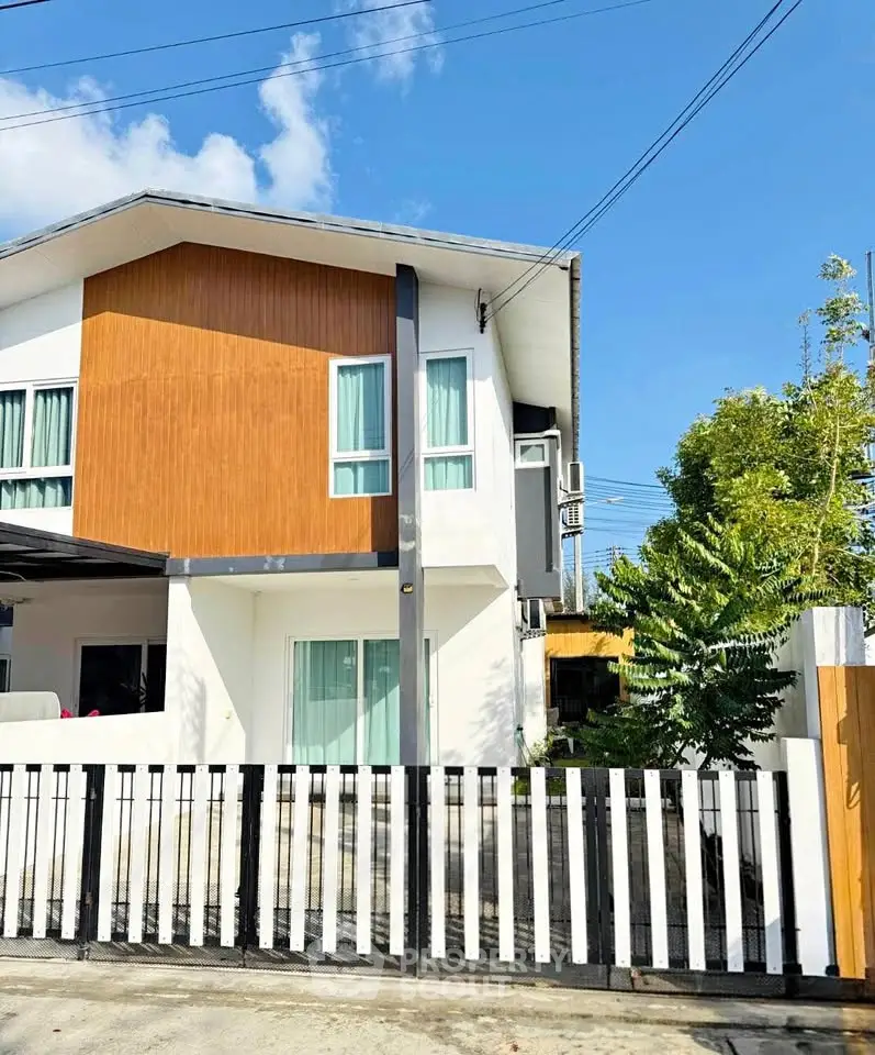 Modern two-story house with stylish facade and gated entrance in sunny neighborhood.