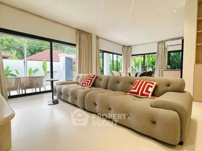 Spacious modern living room with plush sofa and garden view, perfect for relaxation and entertaining.