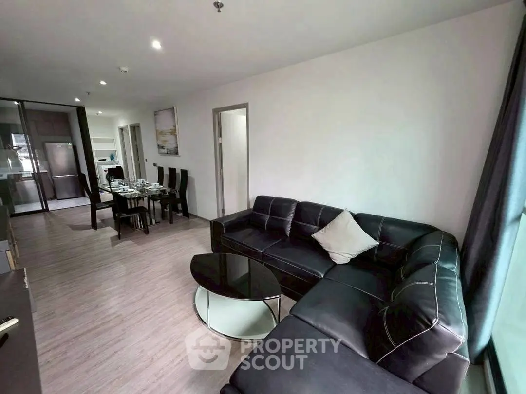 Spacious modern living room with sleek black leather sofa and dining area