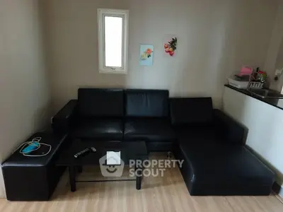 Modern living room with black leather sofa and glass coffee table in cozy apartment.