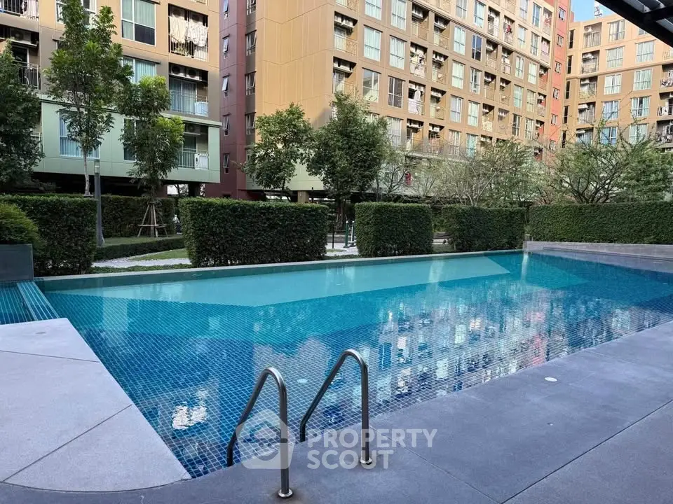 Modern apartment complex with a serene outdoor swimming pool and lush greenery.