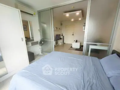 Modern bedroom with sliding glass doors and cozy living area in a stylish apartment.