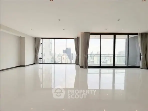Spacious modern living room with floor-to-ceiling windows and stunning city view.