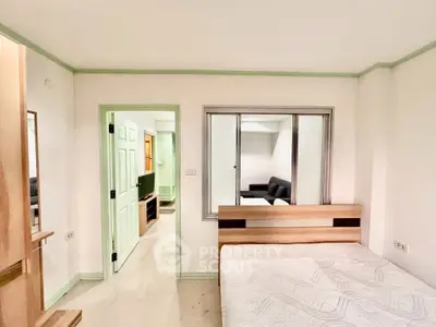 Spacious bedroom with modern decor and adjacent living area in a stylish apartment.
