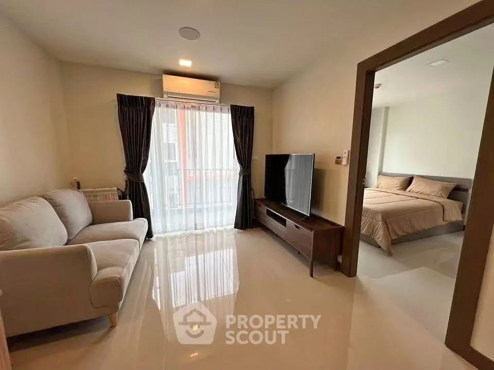 Modern apartment living room with cozy sofa and large TV, adjacent to a stylish bedroom.