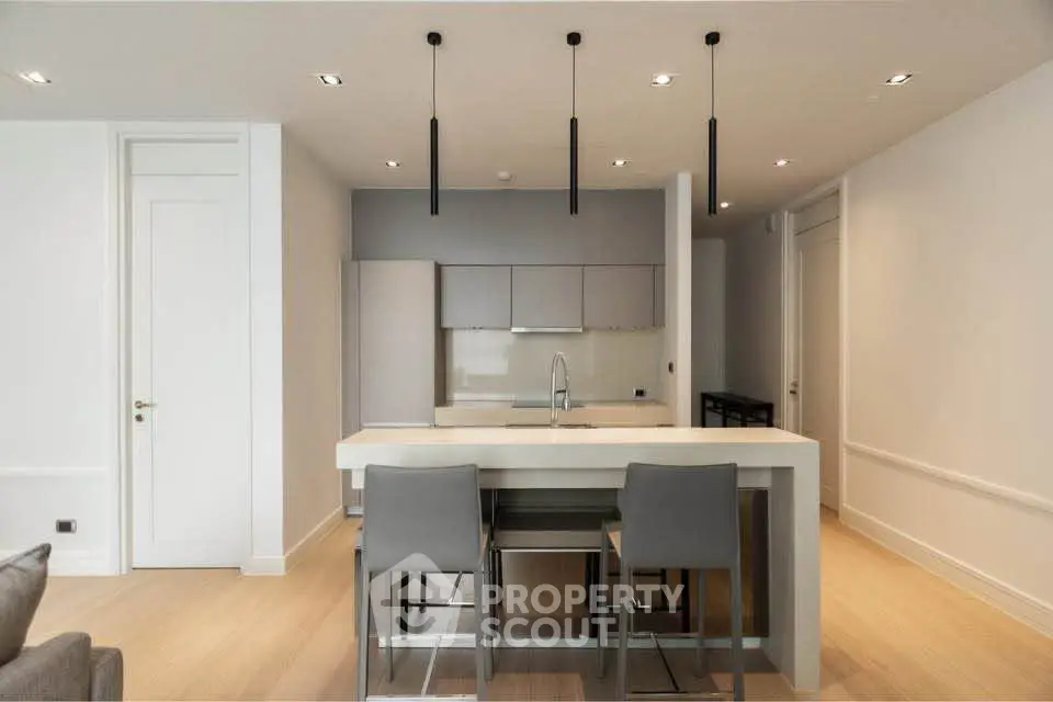 Modern kitchen with sleek design, featuring an island and stylish bar stools in a contemporary apartment.