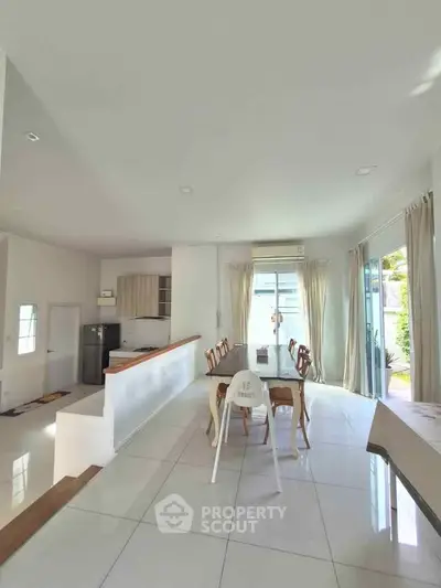 Spacious open-plan living and dining area with modern kitchen and large windows for natural light.