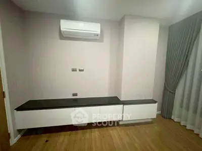 Modern minimalist living room with air conditioning and sleek cabinetry.