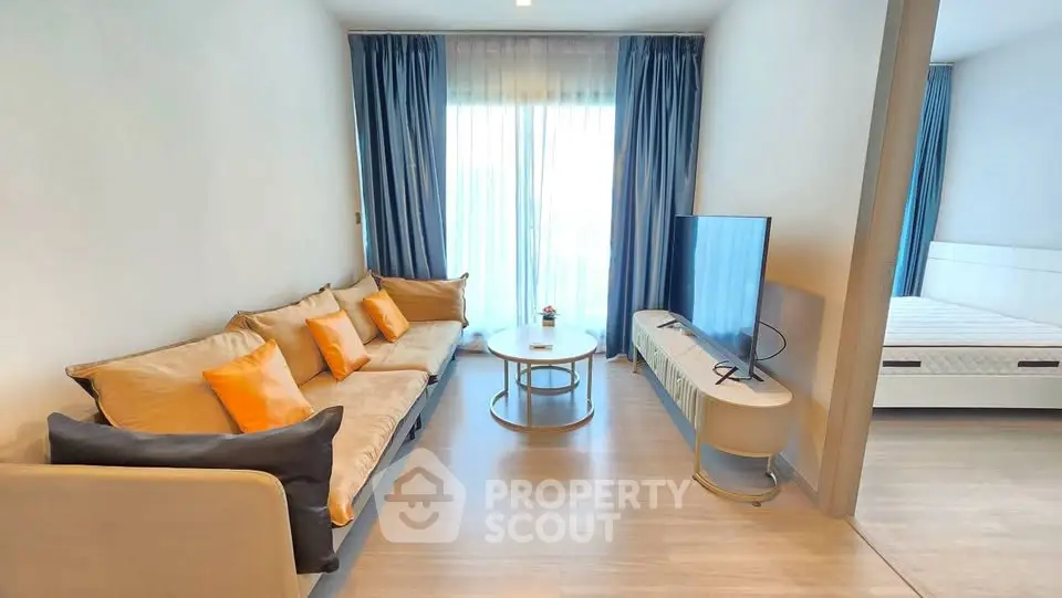 Modern living room with cozy sofa and TV, adjacent to a bright bedroom with natural light.