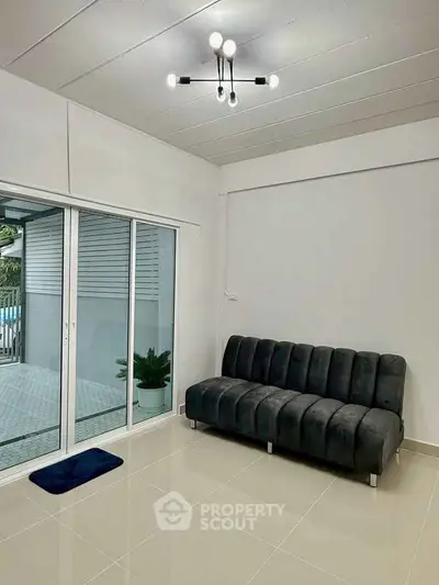 Modern living room with sleek black sofa and sliding glass doors opening to patio.