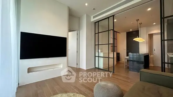 Modern living room with sleek design and large TV, featuring wooden flooring and stylish lighting.