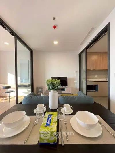 Modern open-plan living room with dining area and kitchen, featuring stylish decor and natural light.
