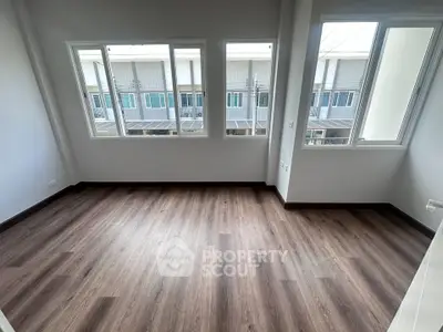 Spacious empty room with large windows and wood flooring