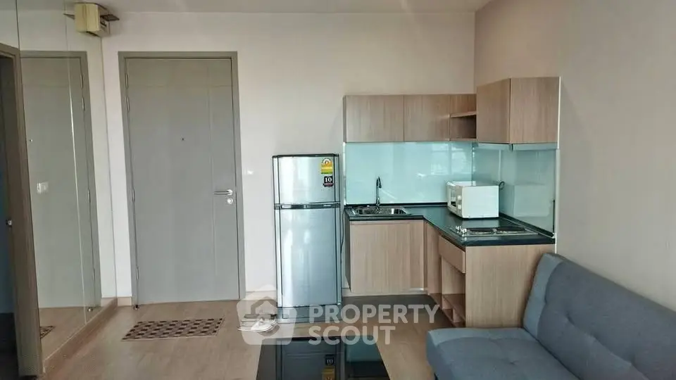 Modern apartment interior with compact kitchen and cozy living area, featuring sleek appliances and stylish decor.