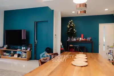 Modern living room with teal accent wall and wooden dining table