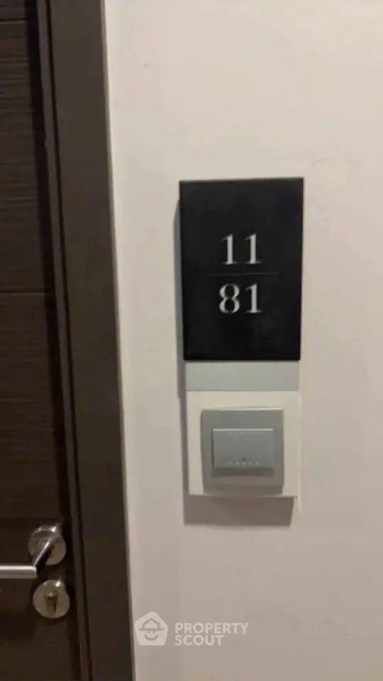 Modern apartment door with room number 11/81 and sleek doorbell.