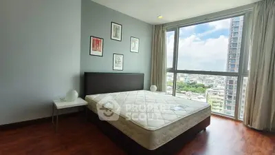 Spacious bedroom with large window offering stunning city views in modern apartment.
