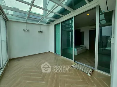 Spacious balcony with glass ceiling and sliding doors, perfect for relaxation.