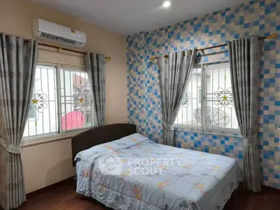 Cozy bedroom with patterned blue accent wall and floral bedding, featuring air conditioning and elegant curtains.
