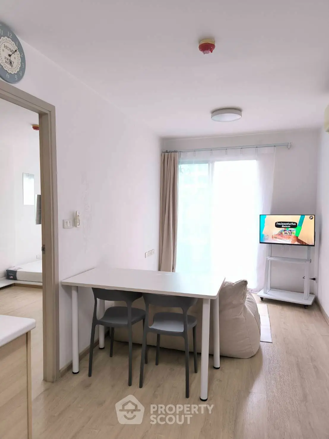 Modern minimalist living area with dining table and TV, bright and inviting space.