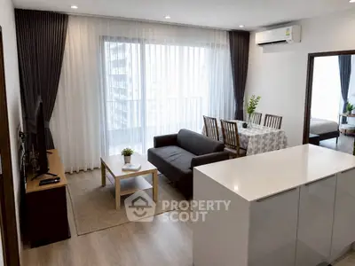 Modern open-plan living room with sleek furniture and large windows in a stylish apartment.