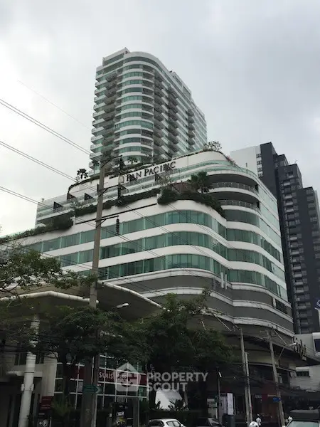 Modern high-rise building with unique architectural design and lush greenery on balconies.