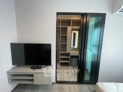 Modern bedroom with TV and walk-in closet featuring sleek sliding doors.
